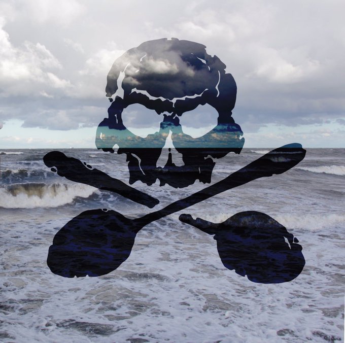 Ein schwarzer Totenkopf mit gekreuzten Löffeln vor einen Meerbild 
